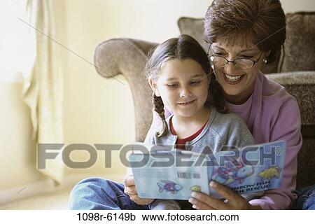 Stock Image - Grandmother and her granddaughter reading a book. Fotosearch