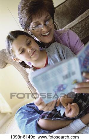 Stock Image - Grandmother and her granddaughter reading a book. Fotosearch