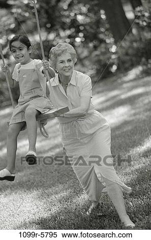 Grandmother pushing her granddaughter on a swing View Large Photo Image Stock Photography - Grandmother pushing her granddaughter on a swing. Fotosearch