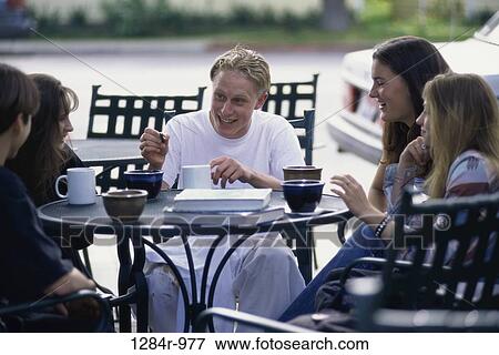 Stock Photo - Group of teenagers sitting at a table outdoors. Fotosearch
