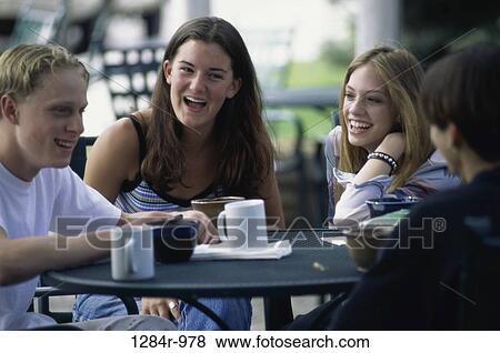 Stock Photo - Group of teenagers sitting at a table outdoors. Fotosearch