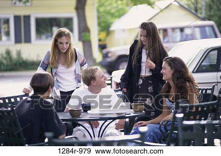 Stock Photo - Group of teenagers sitting at a table outdoors. Fotosearch