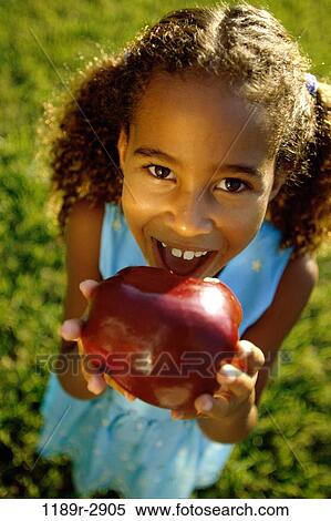 High angle view of a girl holding an apple View Large Photo Image Stock Photography - High angle view of a girl holding an apple. Fotosearch