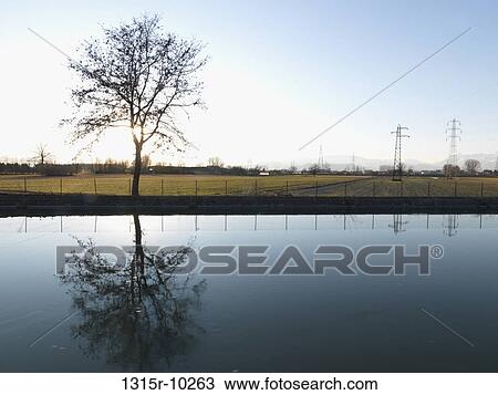 Italy, Canal flows between raised dikes above field, power pylons View Large Photo Image Stock Image - Italy, Canal flows between raised dikes above field, power pylons. Fotosearch