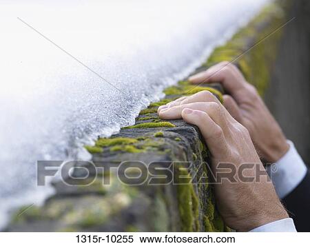 Italy, Hands of businessman cling onto icy, moss covered ledge View Large Photo Image Stock Photography - Italy, Hands of businessman cling onto icy, moss covered ledge. Fotosearch