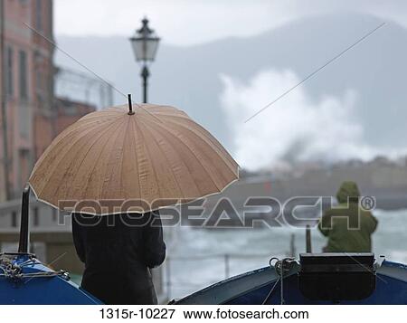 Italy, Liguria, Cinque Terre, Vernazza, Woman watching surf crashing during rain storm View Large Photo Image Stock Photo - Italy, Liguria, Cinque Terre, Vernazza, Woman watching surf crashing during rain storm. Fotosearch