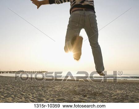 Italy, Liguria, Rear view of man jumping on beach at suise, low section, Liguria, Italy View Large Photo Image Stock Photo - Italy, Liguria, Rear view of man jumping on beach at suise, low section, Liguria, Italy. Fotosearch