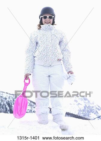 Stock Image - Italy, Piedmont, Bardonecchia, teenage girl holding tobogganing shovel. Fotosearch