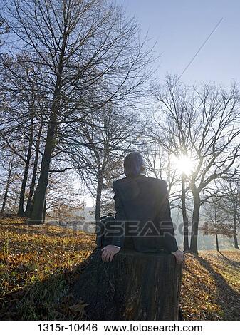 Italy, Piedmont, Businessman sitting on tree trunk at sunrise View Large Photo Image Stock Photograph - Italy, Piedmont, Businessman sitting on tree trunk at sunrise. Fotosearch