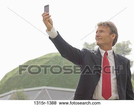 Italy, Piedmont, businessman taking picture with cell phone outside green dome View Large Photo Image Stock Photo - Italy, Piedmont, businessman taking picture with cell phone outside green dome. Fotosearch