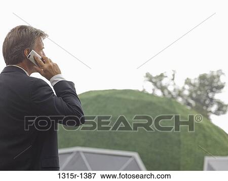 Italy, Piedmont, businessman talking on cell phone outside green dome structure View Large Photo Image Stock Photo - Italy, Piedmont, businessman talking on cell phone outside green dome structure. Fotosearch