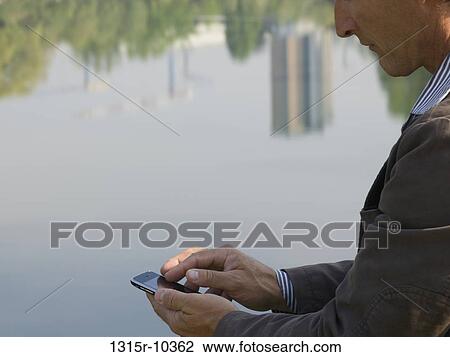 Italy, Piedmont, Close-up of man sending text messaging by river reflection View Large Photo Image Stock Image - Italy, Piedmont, Close-up of man sending text messaging by river reflection. Fotosearch