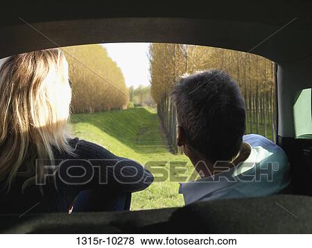 Stock Photo - Italy, Piedmont, Couple look out from car interior to raised dike, planted forest. Fotosearch