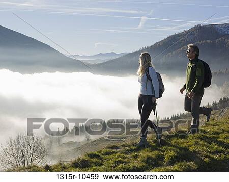 Italy, Piedmont, Couple looking at mountains from meadow above fog View Large Photo Image Stock Photo - Italy, Piedmont, Couple looking at mountains from meadow above fog. Fotosearch