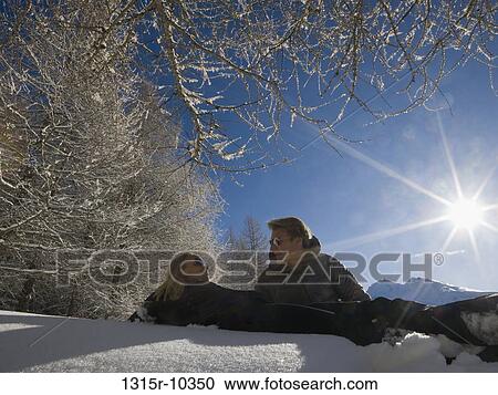 Italy, Piedmont, Couple lying in snow below frosted tree branches View Large Photo Image Stock Image - Italy, Piedmont, Couple lying in snow below frosted tree branches. Fotosearch