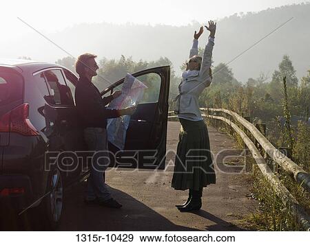 Italy, Piedmont, Couple stretching beside car View Large Photo Image Stock Photo - Italy, Piedmont, Couple stretching beside car. Fotosearch