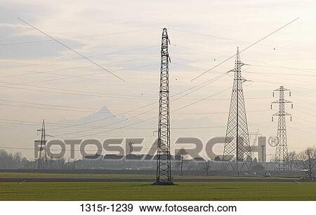 Italy, Piedmont, Electrical pylons rising from newly planted green fields, mountains in background View Large Photo Image Stock Photo - Italy, Piedmont, Electrical pylons rising from newly planted green fields, mountains in background. Fotosearch