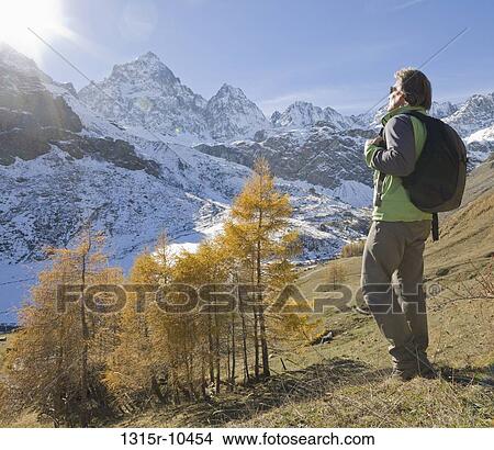 Italy, Piedmont, Hiker looking out to snowcapped mountains View Large Photo Image Picture - Italy, Piedmont, Hiker looking out to snowcapped mountains. Fotosearch