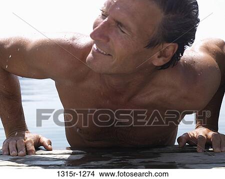 Italy, Piedmont, Lake Orta, Man shaking head while hoisting over pier View Large Photo Image Picture - Italy, Piedmont, Lake Orta, Man shaking head while hoisting over pier. Fotosearch