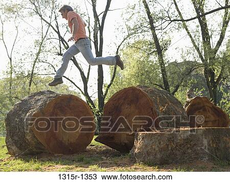 Italy, Piedmont, Man jumping between sawed tree trunks View Large Photo Image Stock Image - Italy, Piedmont, Man jumping between sawed tree trunks. Fotosearch
