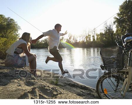 Italy, Piedmont, Man jumping down sandy bank while woman looking away View Large Photo Image Stock Photography - Italy, Piedmont, Man jumping down sandy bank while woman looking away. Fotosearch