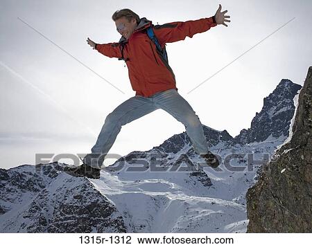 Italy, Piedmont, man jumping from rock in snowy mountains View Large Photo Image Stock Image - Italy, Piedmont, man jumping from rock in snowy mountains. Fotosearch