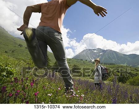 Italy, Piedmont, Man leaping in meadow of wildflowers, woman laughing in background View Large Photo Image Picture - Italy, Piedmont, Man leaping in meadow of wildflowers, woman laughing in background. Fotosearch
