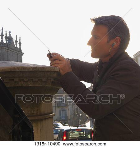 Italy, Piedmont, Man listening to mp3 player in medieval village setting View Large Photo Image Stock Image - Italy, Piedmont, Man listening to mp3 player in medieval village setting. Fotosearch
