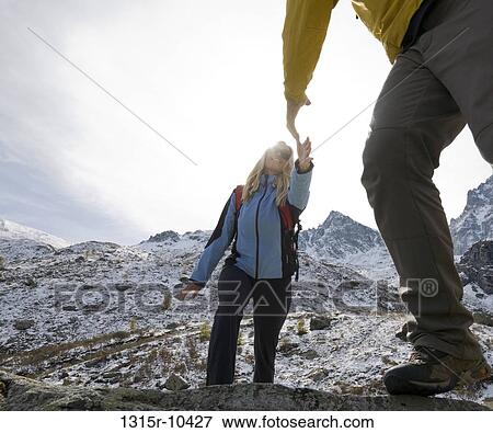 Italy, Piedmont, Man offering helping hand to woman in mountains View Large Photo Image Stock Photo - Italy, Piedmont, Man offering helping hand to woman in mountains. Fotosearch