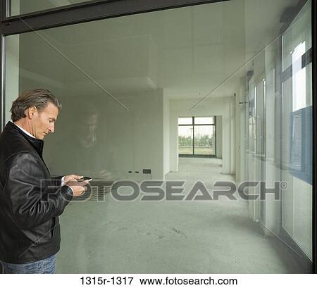 Italy, Piedmont, man sending text message outside empty rental building space View Large Photo Image Stock Photo - Italy, Piedmont, man sending text message outside empty rental building space. Fotosearch