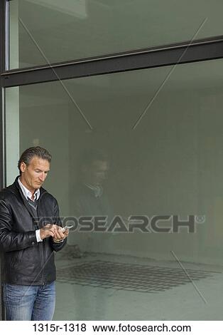 Italy, Piedmont, man sending text message outside empty rental building space View Large Photo Image Stock Photo - Italy, Piedmont, man sending text message outside empty rental building space. Fotosearch