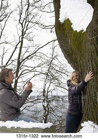 Italy, Piedmont, man taking picture of woman hugging large tree trunk View Large Photo Image Stock Image - Italy, Piedmont, man taking picture of woman hugging large tree trunk. Fotosearch