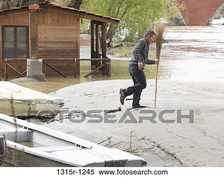 Italy, Piedmont, Man walking in mud with broom View Large Photo Image Stock Photography - Italy, Piedmont, Man walking in mud with broom. Fotosearch