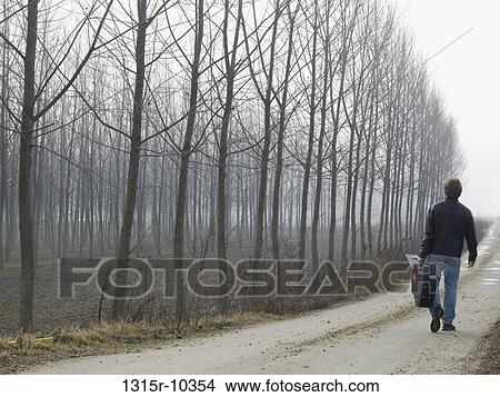 Italy, Piedmont, Man walking up dirt road carrying guitar View Large Photo Image Picture - Italy, Piedmont, Man walking up dirt road carrying guitar. Fotosearch