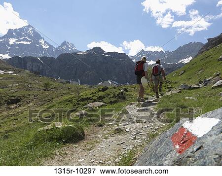 Italy, Piedmont, MonteViso, Hikers walk past trail marker in meadow View Large Photo Image Stock Photo - Italy, Piedmont, MonteViso, Hikers walk past trail marker in meadow. Fotosearch