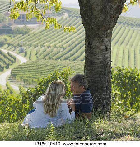 Italy, Piedmont, Rear view of couple toasting wine glasses above vineyard View Large Photo Image Stock Photo - Italy, Piedmont, Rear view of couple toasting wine glasses above vineyard. Fotosearch