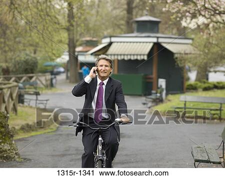 Italy, Piedmont, Turin, businessman cycling through park talking on phone View Large Photo Image Stock Image - Italy, Piedmont, Turin, businessman cycling through park talking on phone. Fotosearch