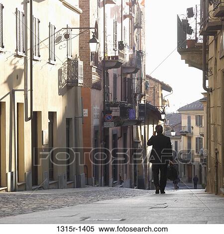 Italy, Piedmont, Turin, businessman walking down medieval street, talking on cell phone View Large Photo Image Stock Photography - Italy, Piedmont, Turin, businessman walking down medieval street, talking on cell phone. Fotosearch