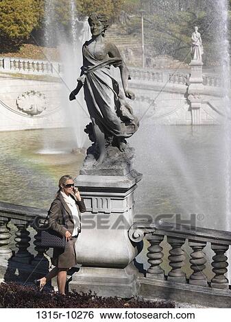 Italy, Piedmont, Turin, Businesswoman walks by fountains in park, talks on phone View Large Photo Image Stock Photograph - Italy, Piedmont, Turin, Businesswoman walks by fountains in park, talks on phone. Fotosearch