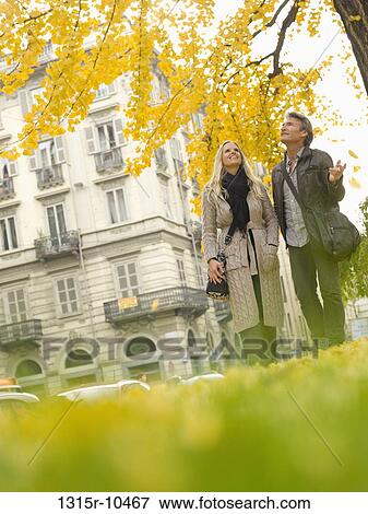 Stock Photo - Italy, Piedmont, Turin, Couple walking under autumn leaves. Fotosearch
