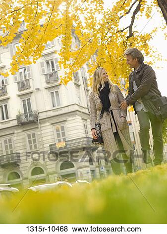 Stock Photo - Italy, Piedmont, Turin, Couple walking under autumn leaves. Fotosearch