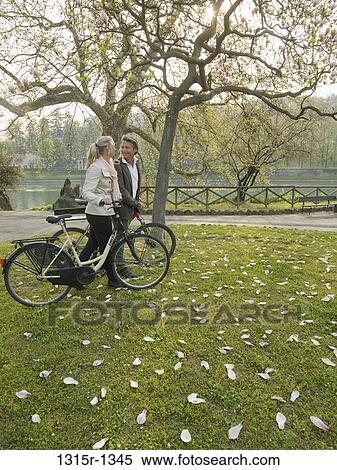 Stock Photography - Italy, Piedmont, Turin, Couple with bicycles in park. Fotosearch