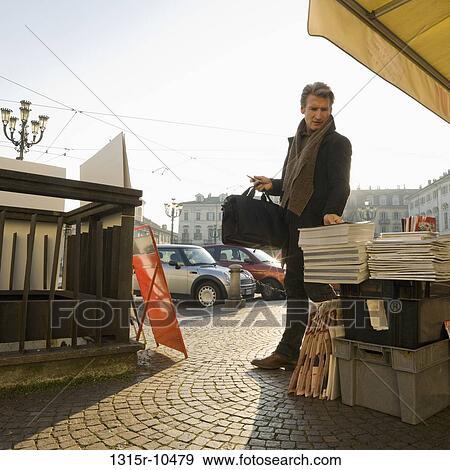 Italy, Piedmont, Turin, man picking up magazine from newspaper stand View Large Photo Image Stock Photo - Italy, Piedmont, Turin, man picking up magazine from newspaper stand. Fotosearch