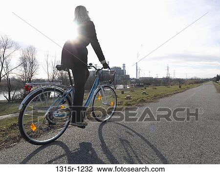 Italy, Piedmont, Woman cycling in winter's day, power plant in background View Large Photo Image Stock Image - Italy, Piedmont, Woman cycling in winter's day, power plant in background. Fotosearch