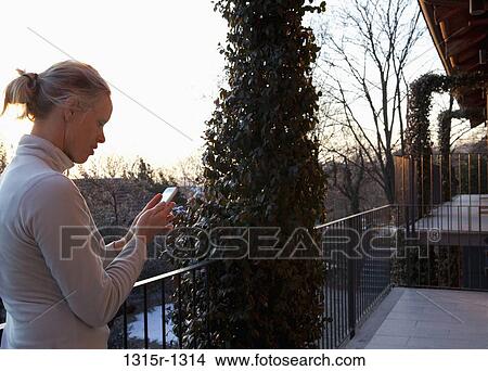 Italy, Piedmont, woman sending text from veranda of apartment building View Large Photo Image Picture - Italy, Piedmont, woman sending text from veranda of apartment building. Fotosearch