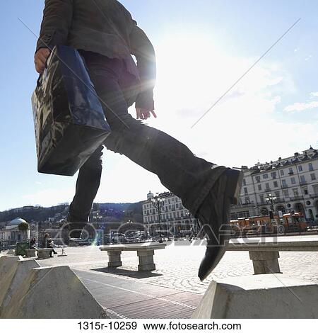 Stock Photo - Italy, Turin, Businessman jumps between concrete blocks in piazza. Fotosearch