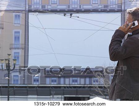Italy, Turin, Businessman talks on cell phone in front of screen, piazza, View Large Photo Image Stock Photo - Italy, Turin, Businessman talks on cell phone in front of screen, piazza,. Fotosearch