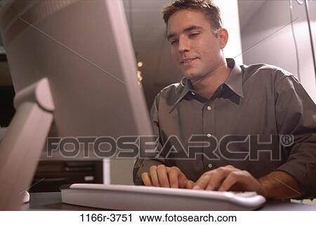 Low angle view of a businessman sitting in front of a computer monitor View Large Photo Image Stock Image - Low angle view of a businessman sitting in front of a computer monitor. Fotosearch