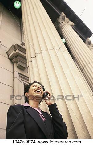 Picture - Low angle view of a businesswoman talking on a mobile phone smiling. Fotosearch