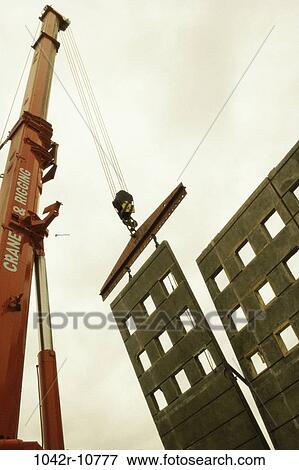 Low angle view of a crane carrying a section of a building View Large Photo Image Stock Photo - Low angle view of a crane carrying a section of a building. Fotosearch